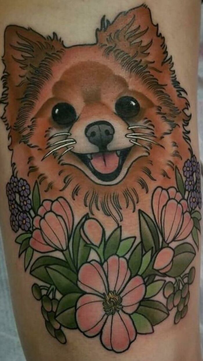 Pet tattoo of a smiling dog surrounded by colorful flowers.