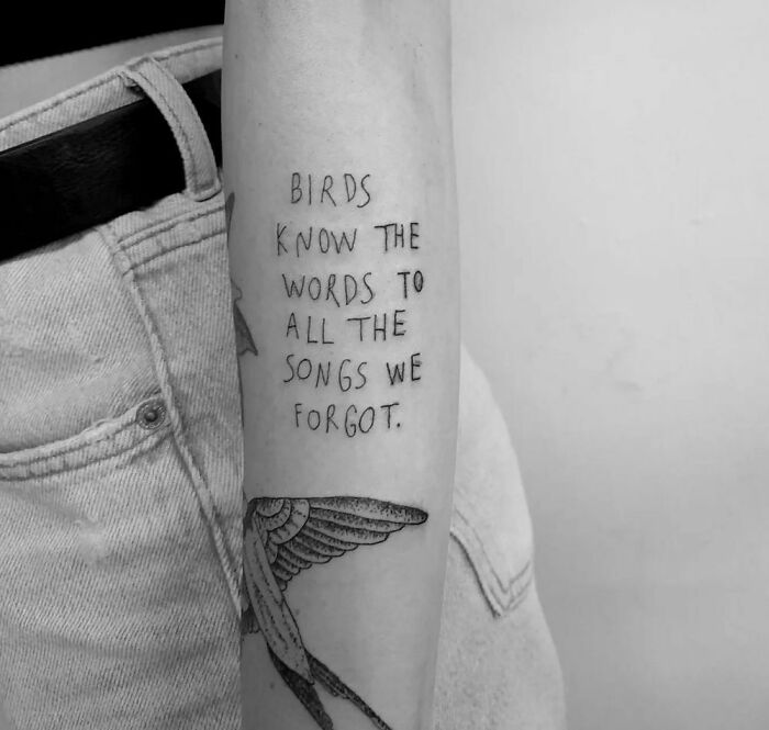 Arm with "Birds know the words..." tattoo, highlighting meaningful word tattoos.