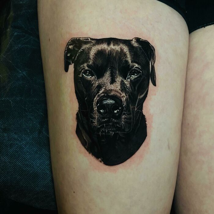Pet tattoo of a black dog's face on skin, celebrating furry friends.