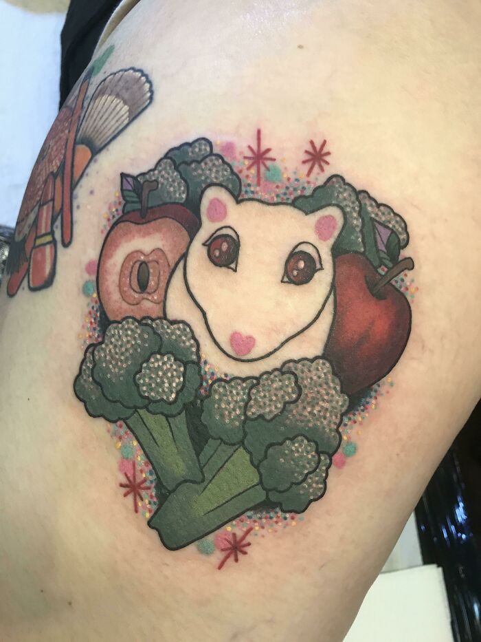 Adorable pet tattoo of a hamster with apples and broccoli, showcasing a loving tribute to a cherished animal companion.
