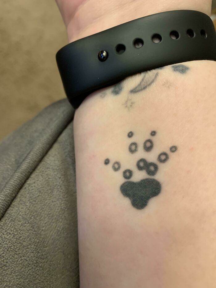 Paw print tattoo on a wrist, symbolizing love for furry friends.