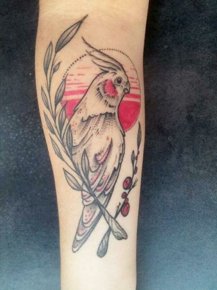 A pet tattoo featuring a cockatiel perched on a branch, celebrating the bond between humans and pets.