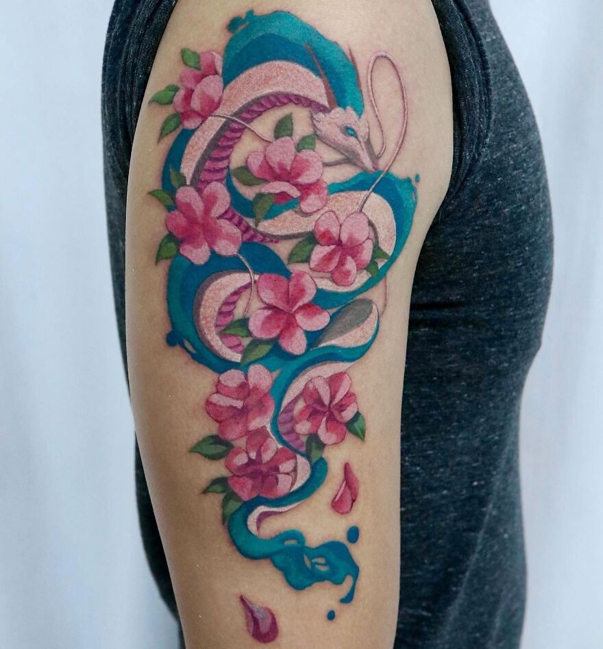 Watercolor tattoo featuring a blue snake and pink flowers on an arm.