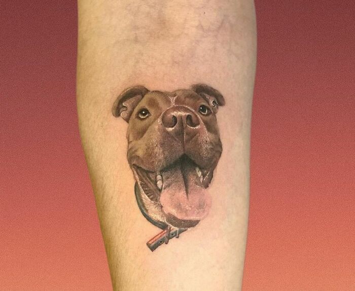 Pet tattoo of a happy dog's face on an arm, showcasing the bond between humans and pets.
