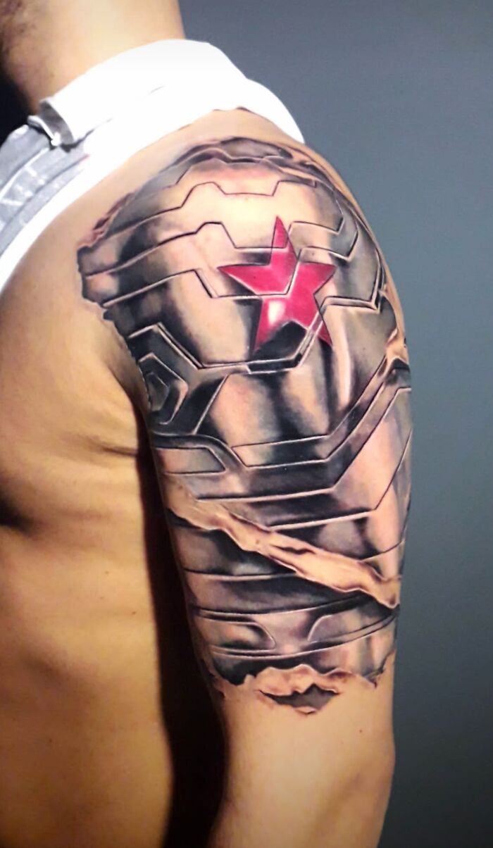 Arm tattoo inspired by Marvel superhero Winter Soldier, featuring a metallic look with a red star on the shoulder.