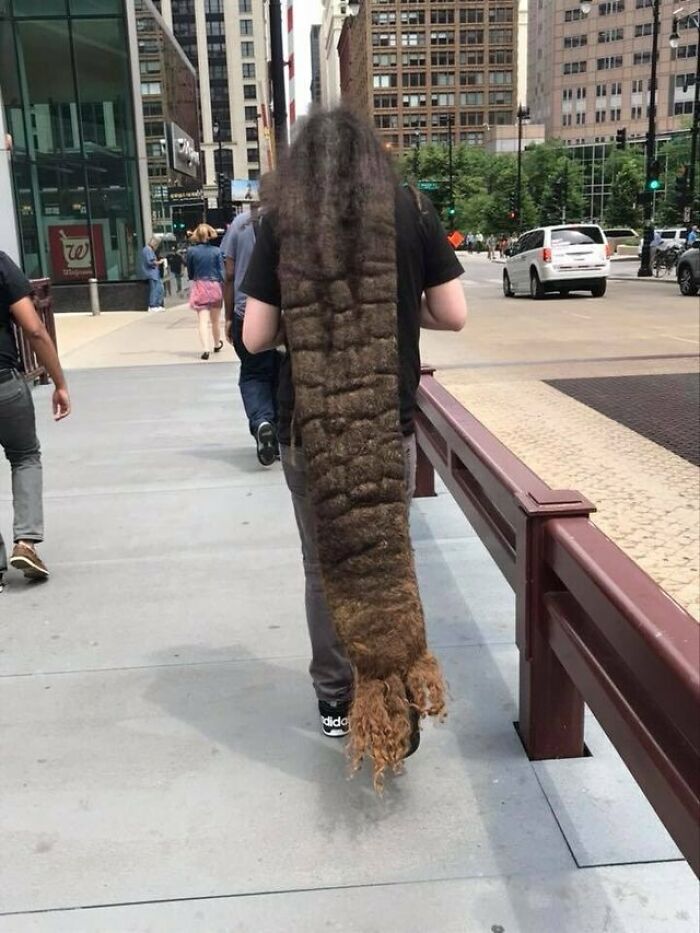 Person with extremely long, layered hairstyle on a city sidewalk, exemplifying unusual bad haircut ideas.