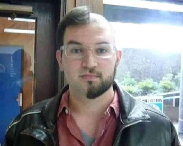Person with an unusual asymmetrical haircut, wearing glasses and a leather jacket, showcasing unique bad haircut ideas.