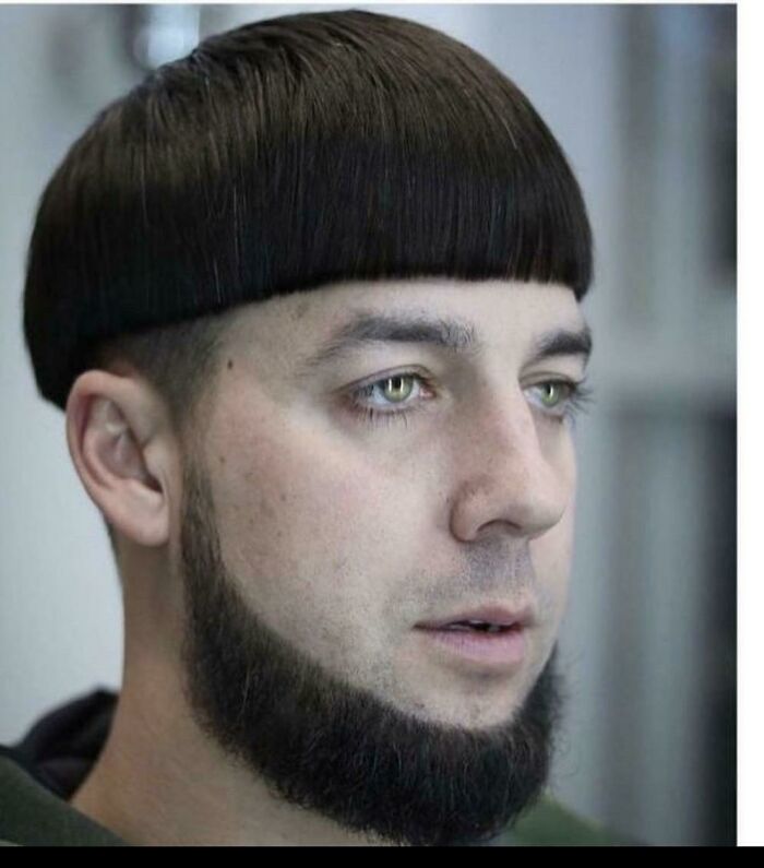 Unusual haircut idea with straight fringe, paired with a thick beard, creating a striking style contrast.