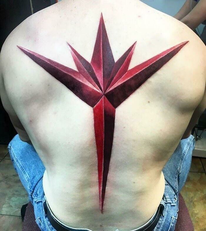 Red geometric Marvel tattoo design on a person's back.