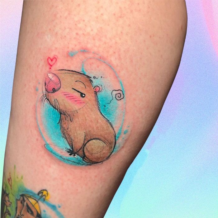 Adorable pet tattoo of a cartoon mole with a heart above its head, inked on a person's arm.