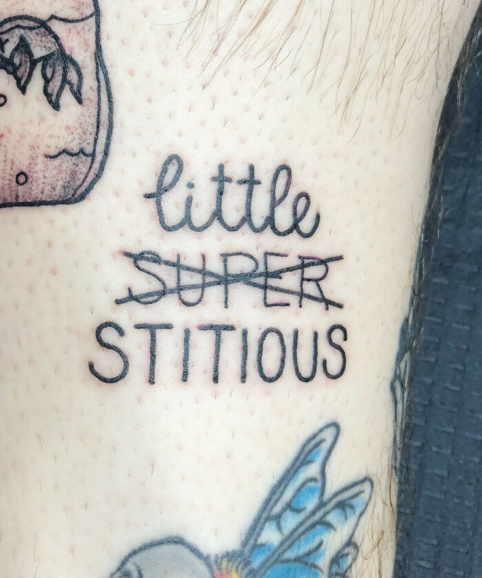 Creative word tattoo reading "little stitious" with "super" crossed out, next to a colorful butterfly design.