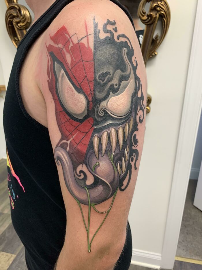 Arm tattoo of comic character Venom with a half Spider-Man mask, showcasing detailed Marvel art.