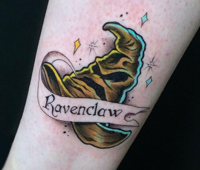 Harry Potter tattoo featuring the Sorting Hat with a "Ravenclaw" banner, surrounded by colorful stars.