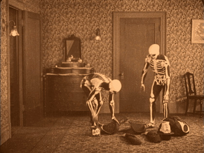 Two skeletons in an old room with broken pottery, illustrating historical events from around a century ago.