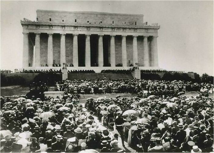 Large crowd gathered with umbrellas in front of Lincoln Memorial, illustrating big historical events from around a century ago.