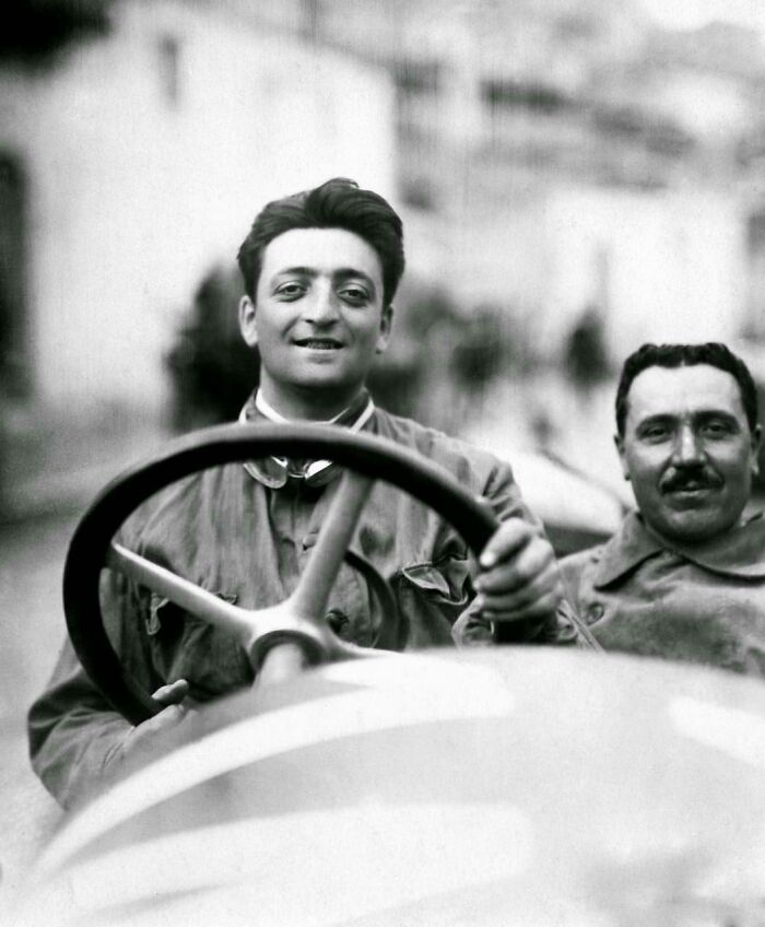 Two men smiling in an old car, representing notable historical events from around a century ago highlighted by netizens.