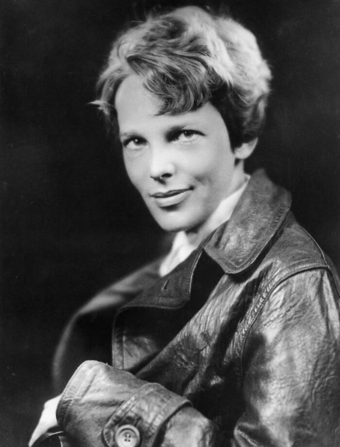 Black and white portrait of a confident woman in a leather jacket, representing big historical events from around a century ago.