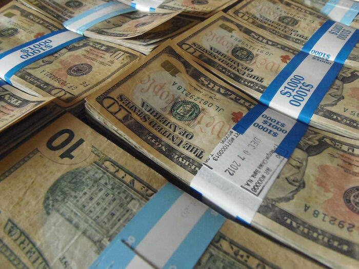 Stacks of US dollar bills bundled with blue bands, illustrating stories of what doesn't work as told by professionals.