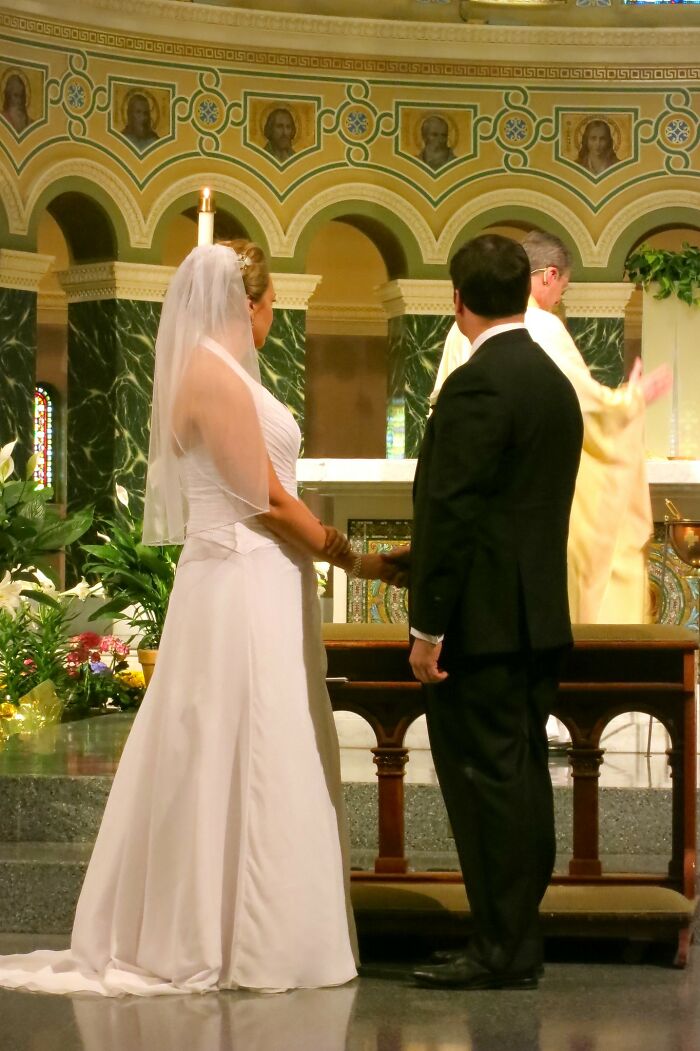 Bride and groom stand at the altar, exchanging vows in a beautifully decorated church setting.