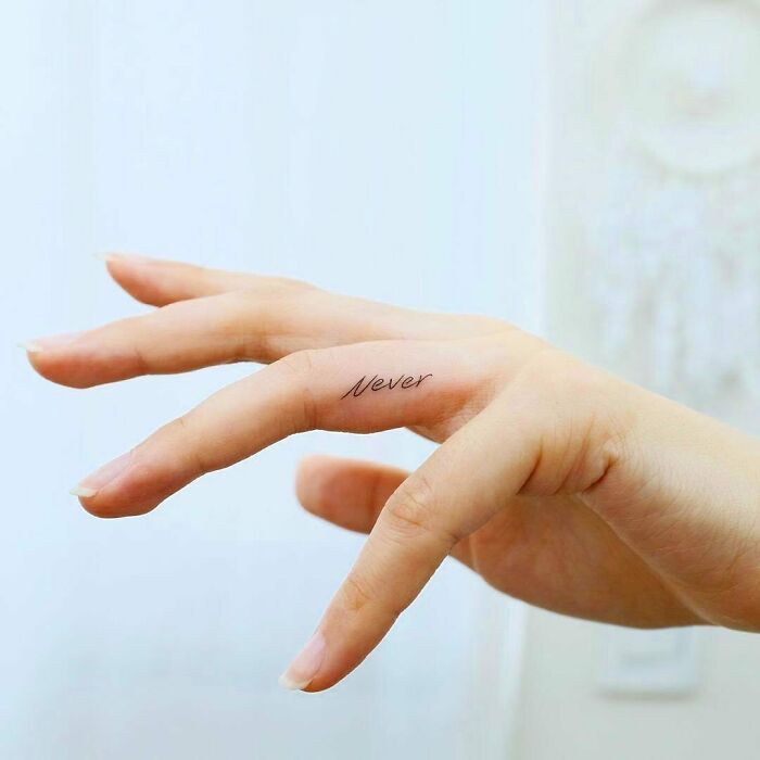 "Creative word tattoo 'Never' inked on a finger, showcasing minimalist style for inkspiration."