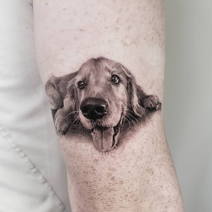 Pet tattoo of a dog's face on an arm, capturing an adorable and lifelike expression.