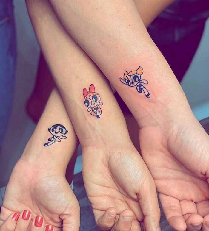 Three wrists displaying matching cartoon-themed best friend tattoos.