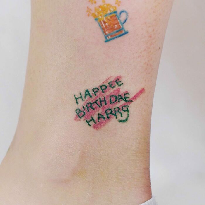 Harry Potter tattoo on ankle with "Happee Birthdae Harry" text in colorful ink.