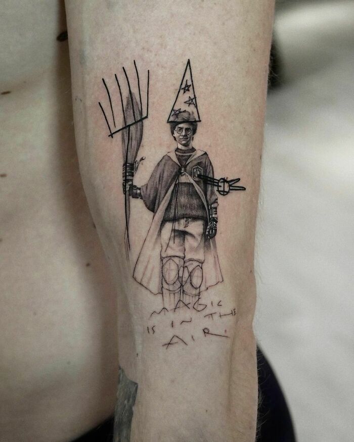 Wizarding World tattoo on forearm depicting a person with a wizard hat and broom, text reads "Magic is in the air."