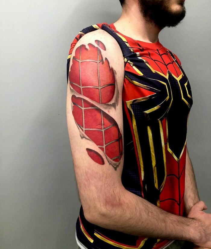 Marvel tattoo of Spider-Man design on a man's arm, wearing a Spider-Man themed shirt, showing intricate detail.