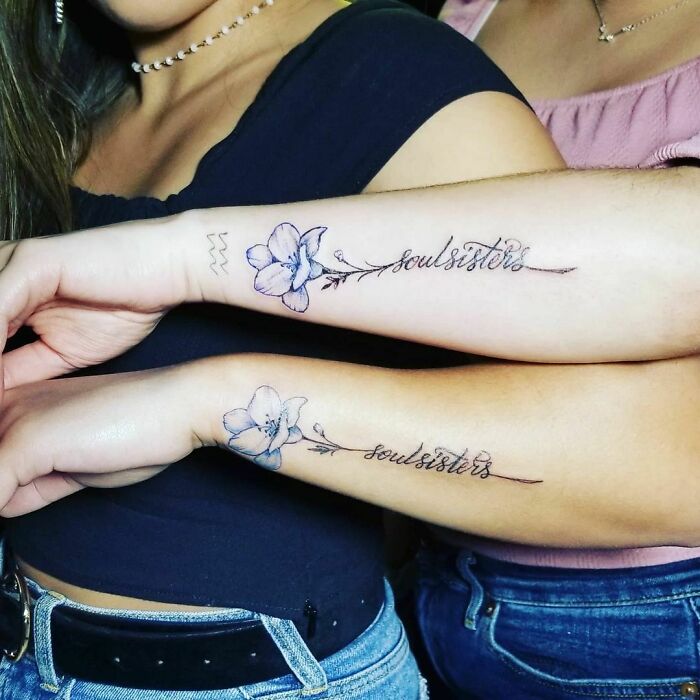 Matching BFF tattoos with flowers and "soul sisters" text on forearms, symbolizing friendship.