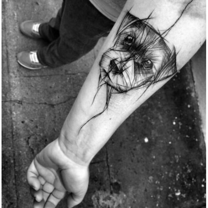 Sketch-style pet tattoo of a dog's face on a person's forearm, celebrating furry friends.