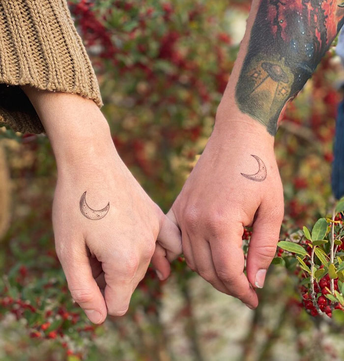 Matching crescent moon tattoos on friends' hands to symbolize friendship.
