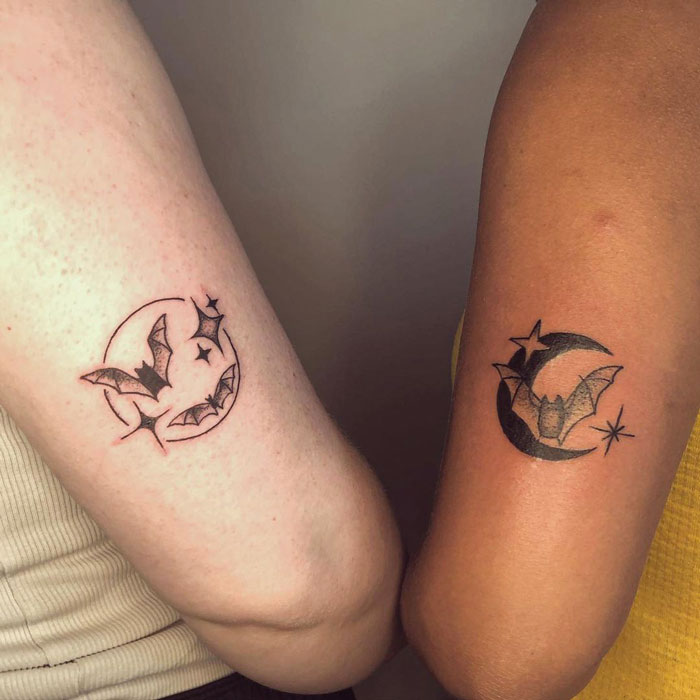 Matching moon and bat friend tattoos on two arms, symbolizing everlasting friendship.