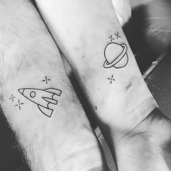 Brother and sister tattoos featuring a rocket and planet design on forearms, symbolizing connection and unity.