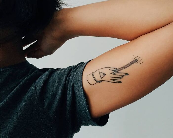 Minimalist Harry Potter tattoo of a hand holding a wand on an arm, perfect for ultimate wizarding world fans.