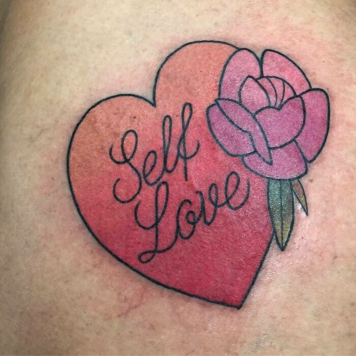 Heart-shaped tattoo with "Self Love" and pink rose, showcasing creative word tattoos for inspiration.