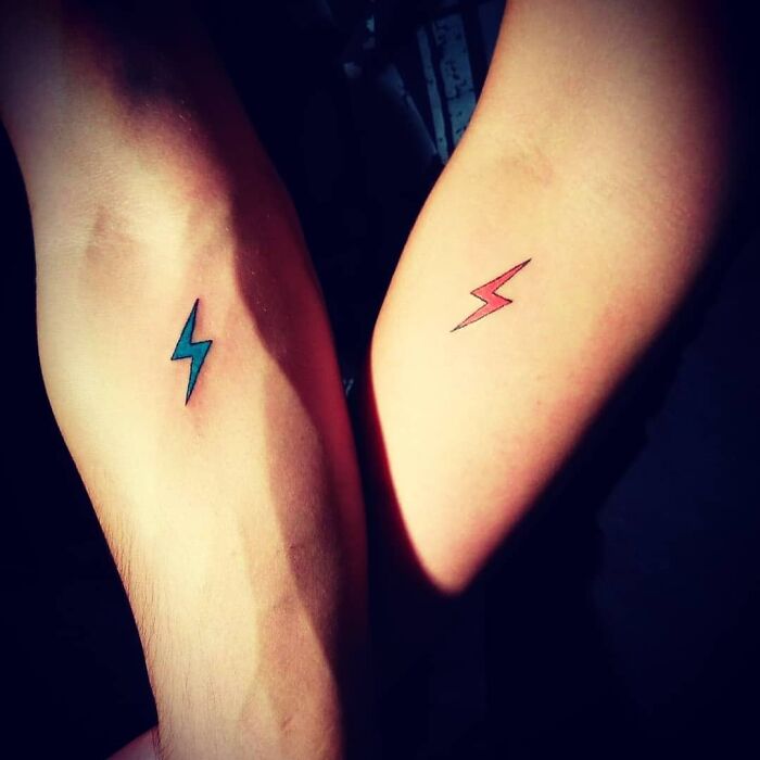 Brother and sister tattoos featuring matching lightning bolt designs in blue and red on arms.