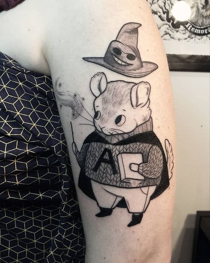 A whimsical Harry Potter tattoo featuring a mouse dressed as a wizard with a wand and hat.