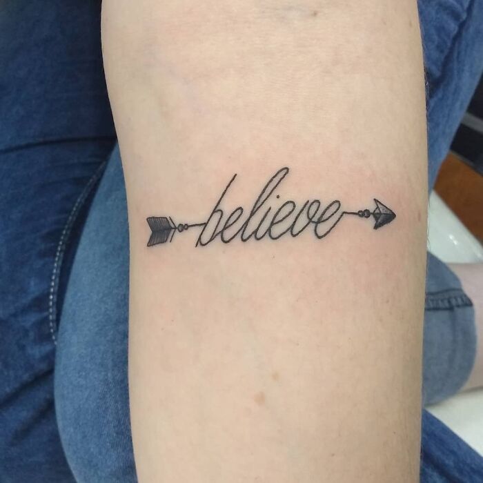 "Creative word tattoo with 'believe' and arrow design on arm."