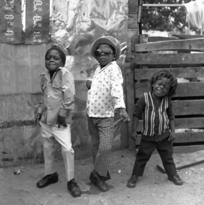 Three young and happy boys standing near a fence 