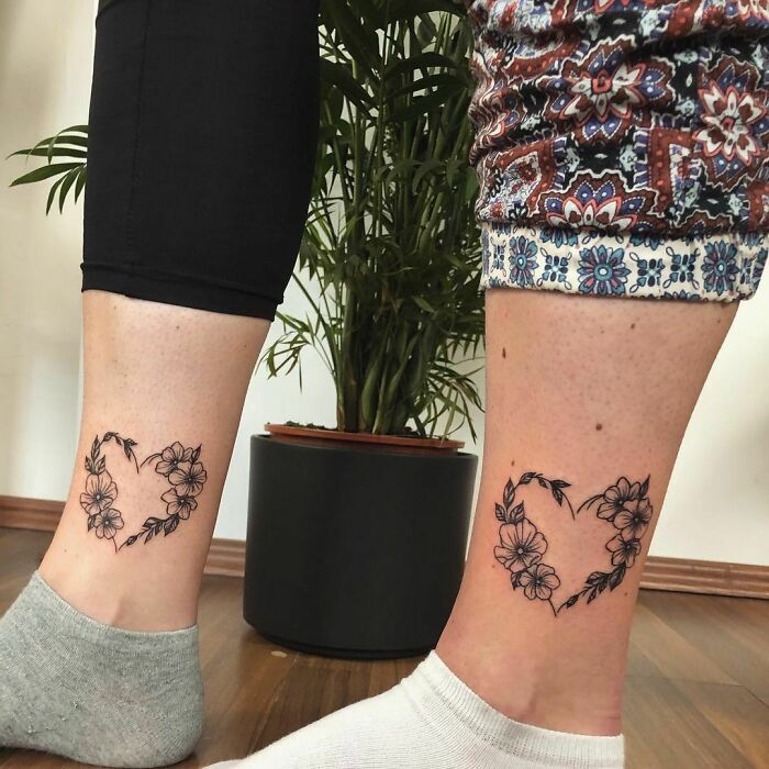 Matching floral heart tattoos on siblings' ankles, symbolizing brother and sister bond.