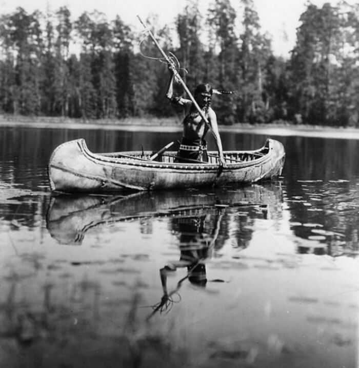 Native American in a boat in the middle of the lake spearfishing 