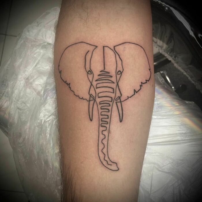 Single-line tattoo of an elephant on a person's arm, showcasing minimalist artistic design.