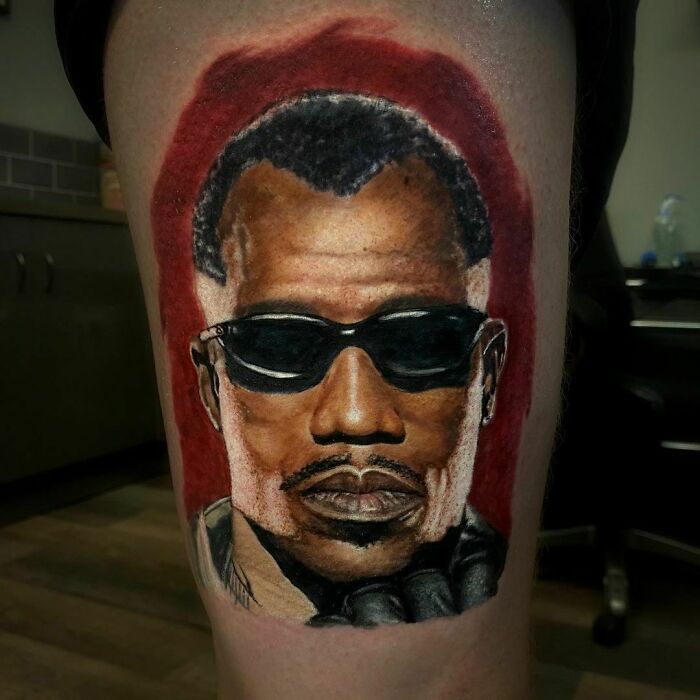 Marvel tattoo of a superhero Blade wearing sunglasses in vibrant colors on the arm inside a tattoo studio.