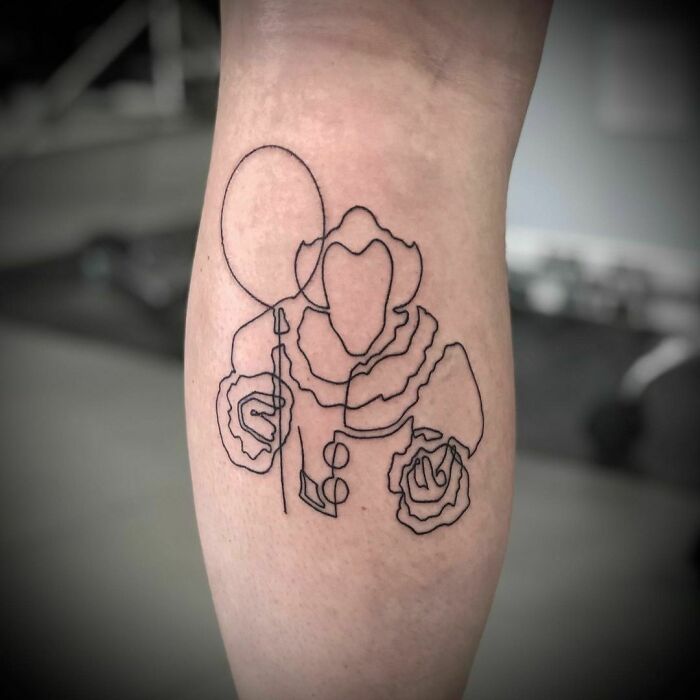 Single-line tattoo of a clown holding a balloon, elegantly drawn on a forearm.