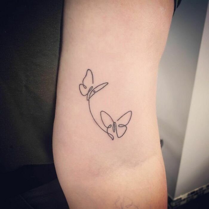 Single-line tattoo of three butterflies on a person's arm, illustrating simple yet elegant design.