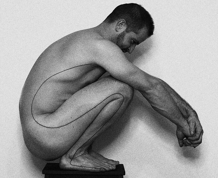 Man displaying a single-line tattoo along his side in a crouched position, highlighting fine-line perfection.