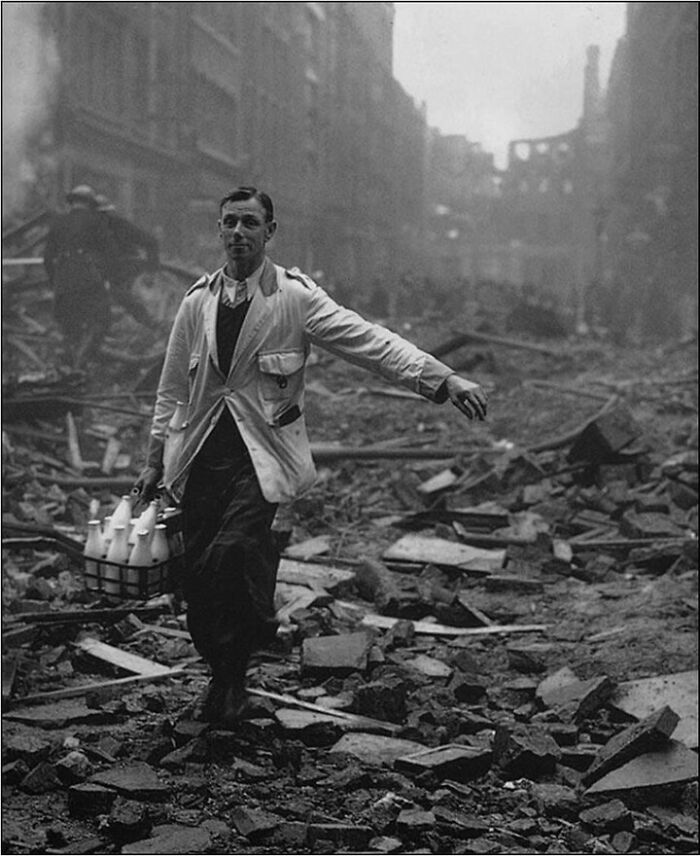 Milkman walking on a street full of building debris on the street 