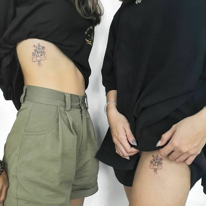 Brother and sister showing matching small tattoos with floral designs on their sides.