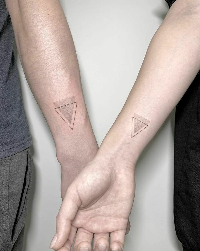 Brother and sister show matching simple triangle tattoos on their forearms.
